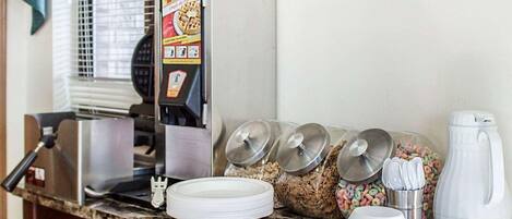 A breakfast bar with a waffle maker, cereal dispensers, and a coffee maker.