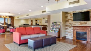 A modern living room with a sofa, ottoman, fireplace, and a TV mounted on the wall.