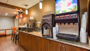 A coffee station with a coffee machine, cups, and a beverage dispenser.