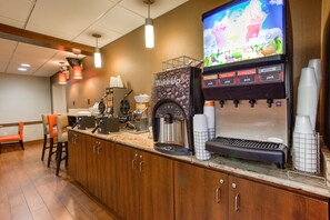 A coffee station with a coffee machine, cups, and a beverage dispenser.