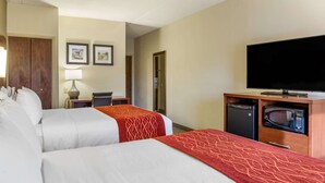 A hotel room with two beds, a TV, a microwave, and a desk with a lamp.