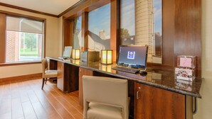 A reception desk with a computer, a chair, and a window with a view of a silo.
