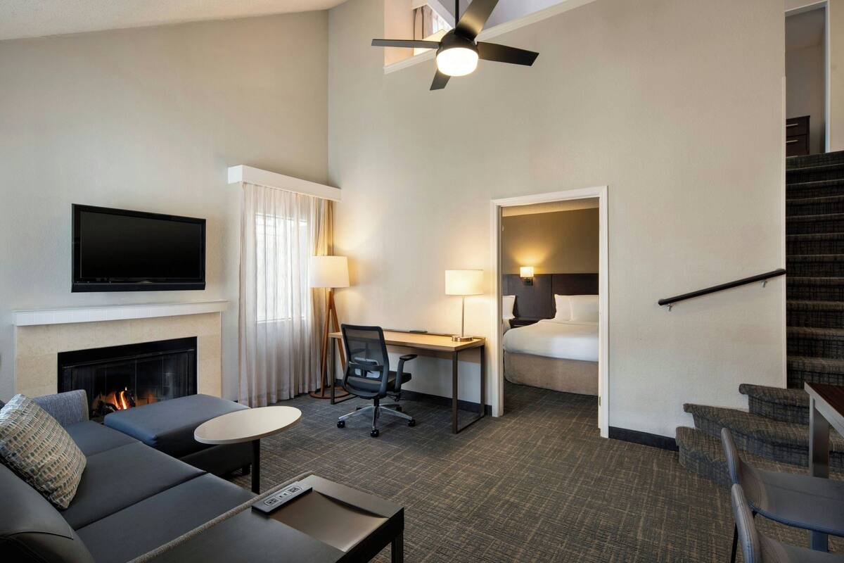 Une chambre d’hôtel équipée d’un canapé, d’un bureau, d’une télévision, d’une cheminée, d’un escalier et d’un ventilateur de plafond.