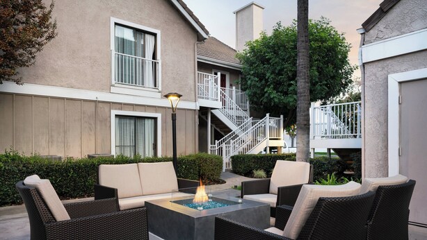 A patio area with a fire pit, wicker furniture, and a staircase leading to an upper level. - Residence Inn by Marriott Anaheim Placentia Fullerton (Placentia)
