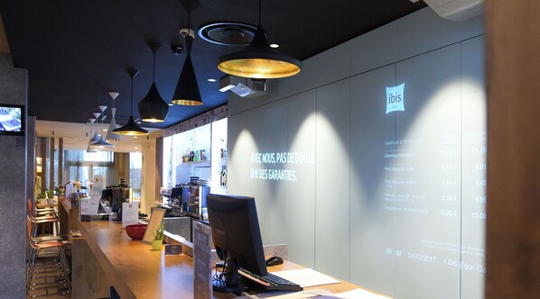 A modern hotel lobby with a reception desk, computer, and seating area. - ibis Dijon Gare (Dijon)