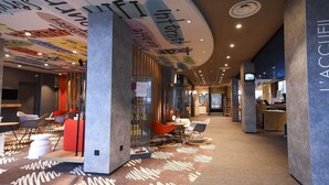 Un moderno vestíbulo de hotel con un área de estar central, una recepción y una alfombra estampada.