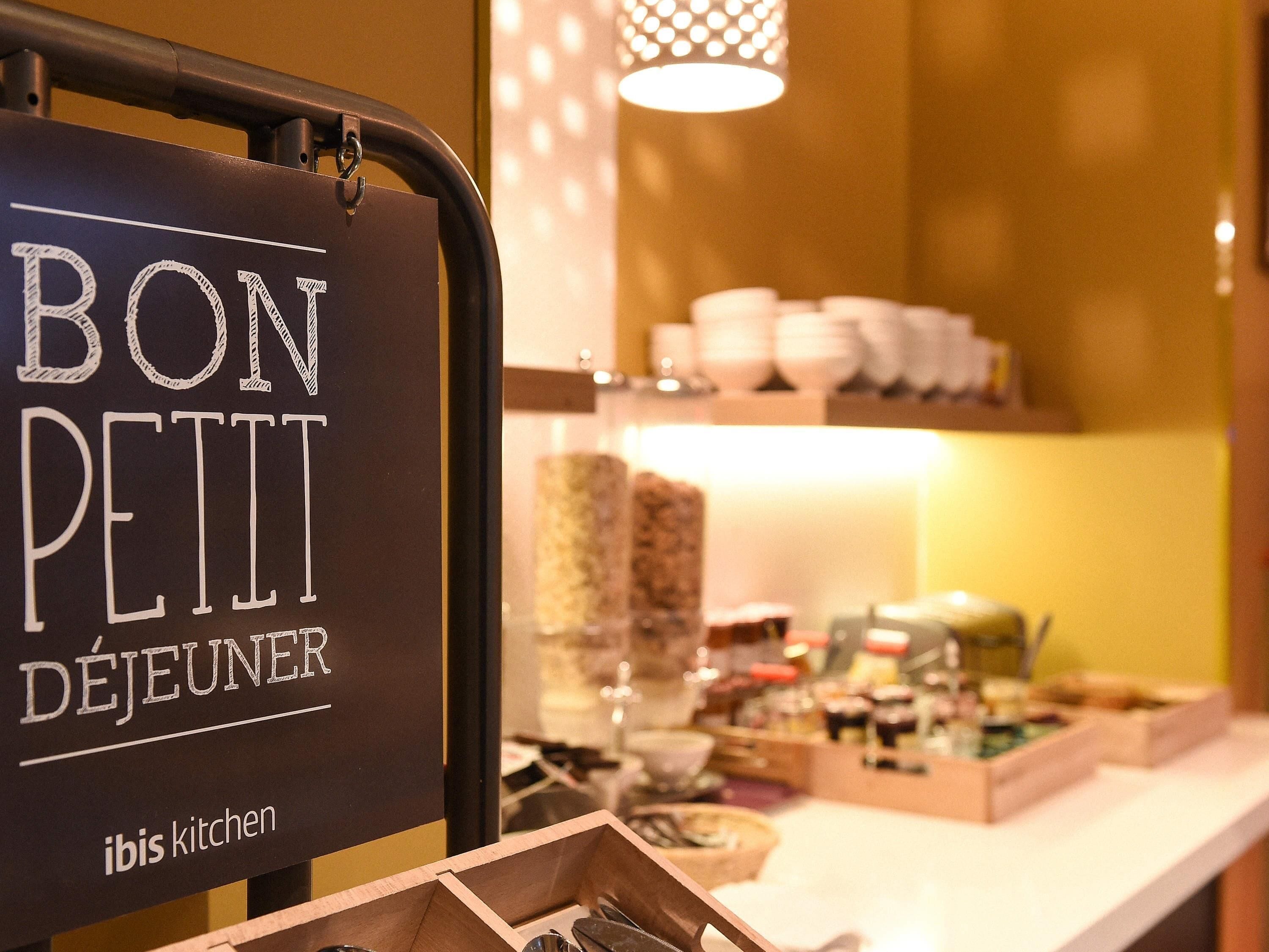 Una encimera de cocina con un cartel que dice 'BON PETIT DEJEUNER' e 'ibis kitchen'.