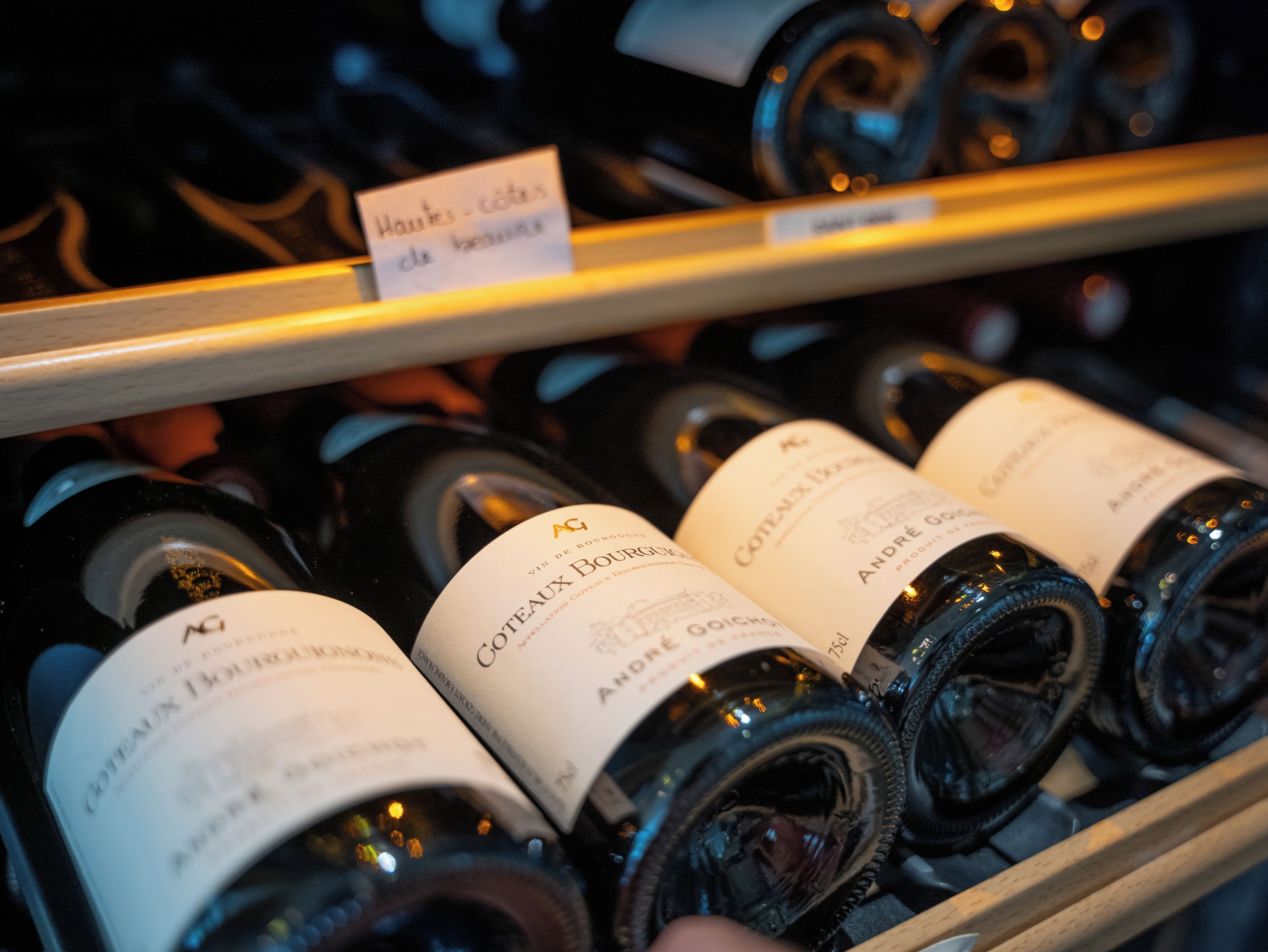 A selection of wine bottles on a shelf, with labels indicating they are from the Coteaux Bourgeois region.