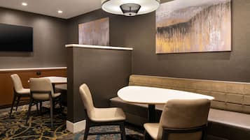 A conference room with a large table, four chairs, a sofa, and a flat-screen TV on the wall.