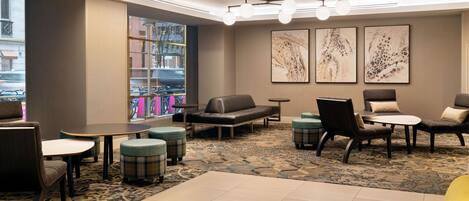 A hotel lobby with seating areas, a coffee table, and a bookshelf.