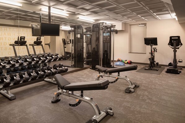 Un gimnasio con equipo de ejercicios, cintas de correr y mancuernas.