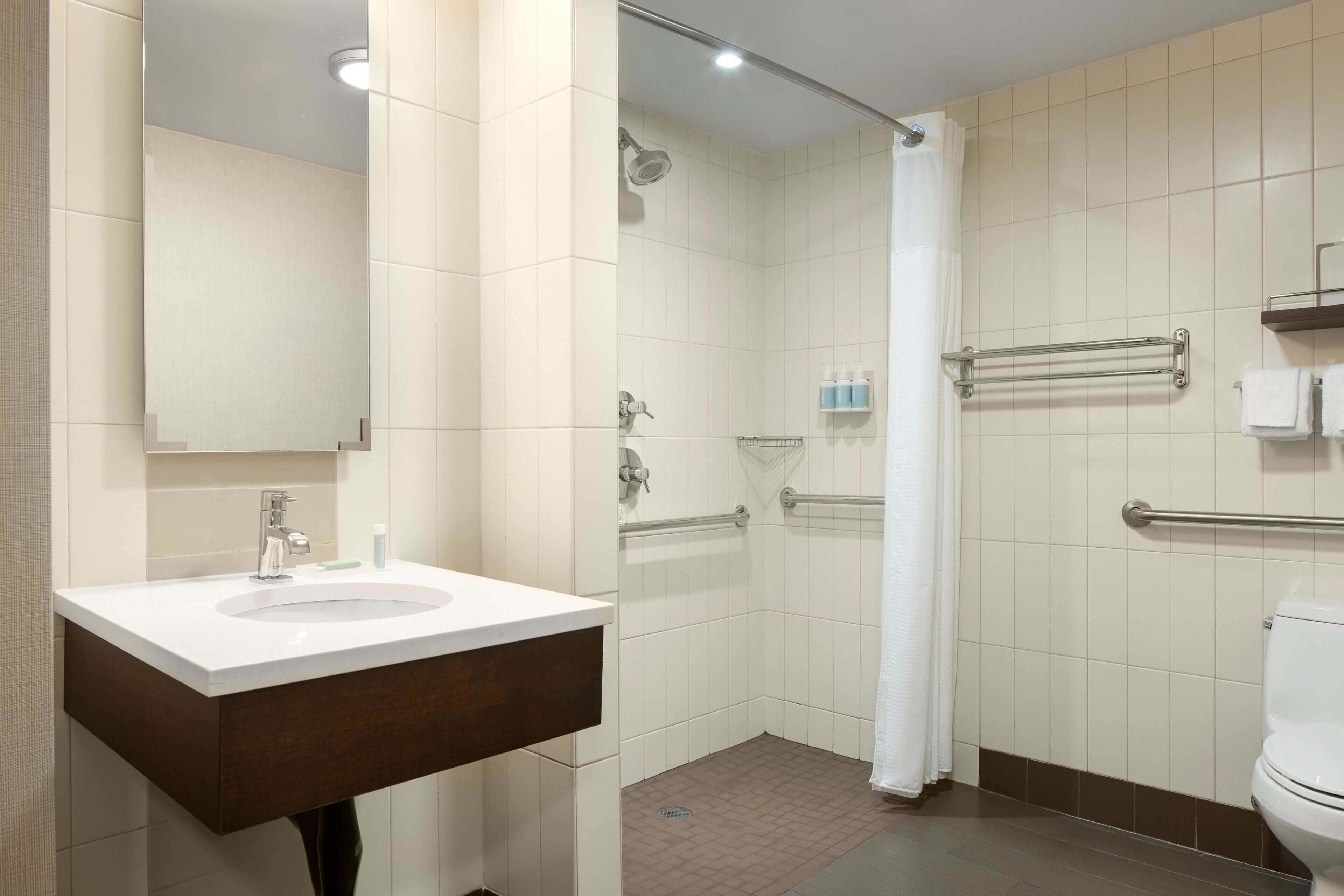 A modern bathroom with a white sink, a shower, and a toilet.