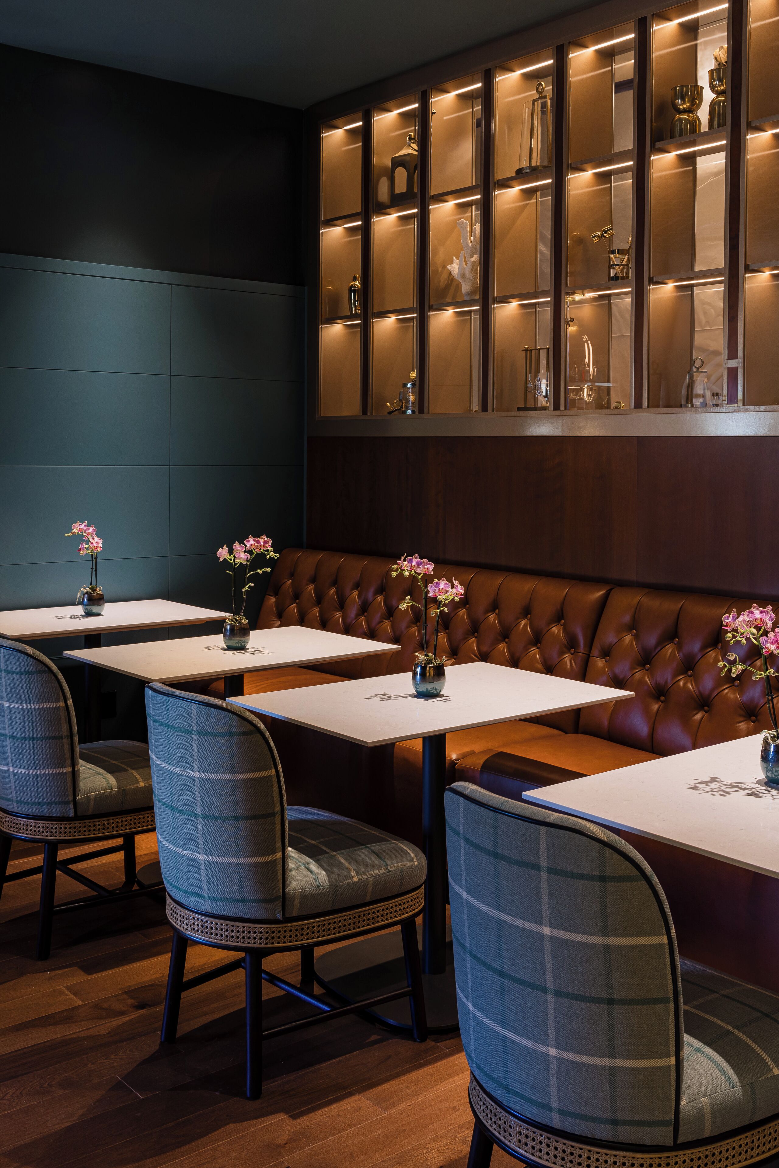 A restaurant interior with booths, tables, and a display case with glassware.