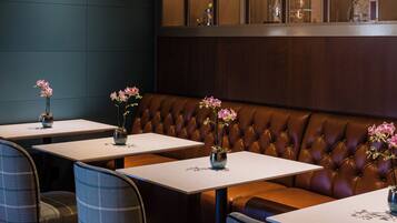 A restaurant interior with booths, tables, and a display case with glassware.