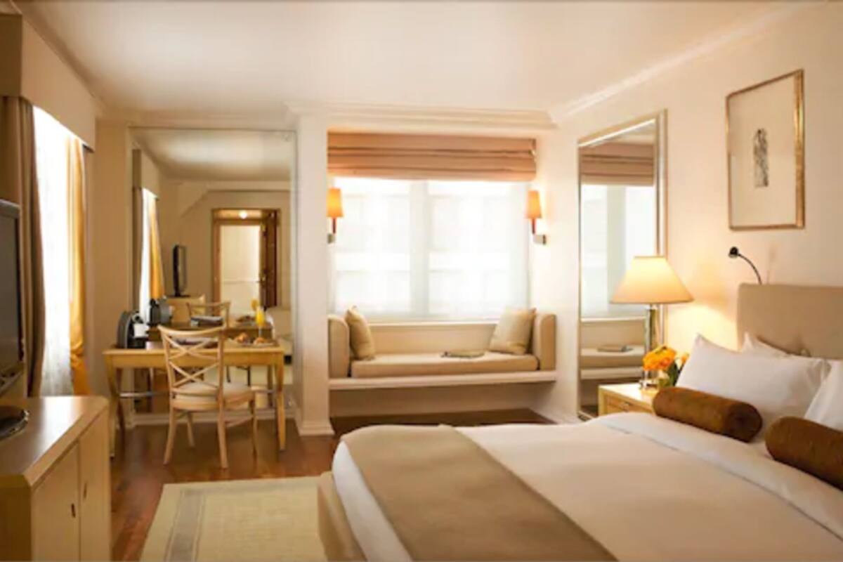 A hotel room with a bed, a desk, a chair, a television, and a window with curtains.