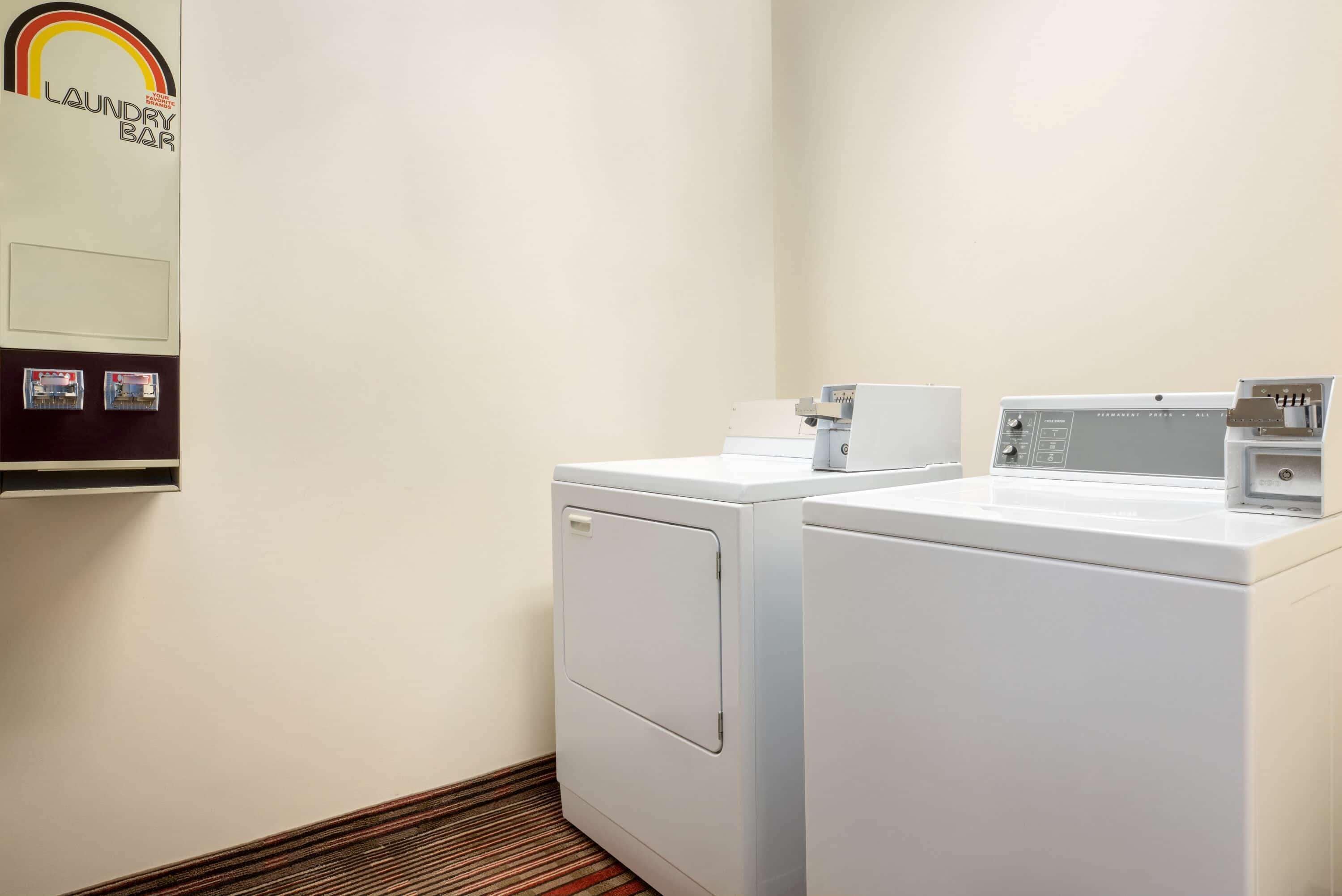 A laundry facility with two white washing machines and a dryer.