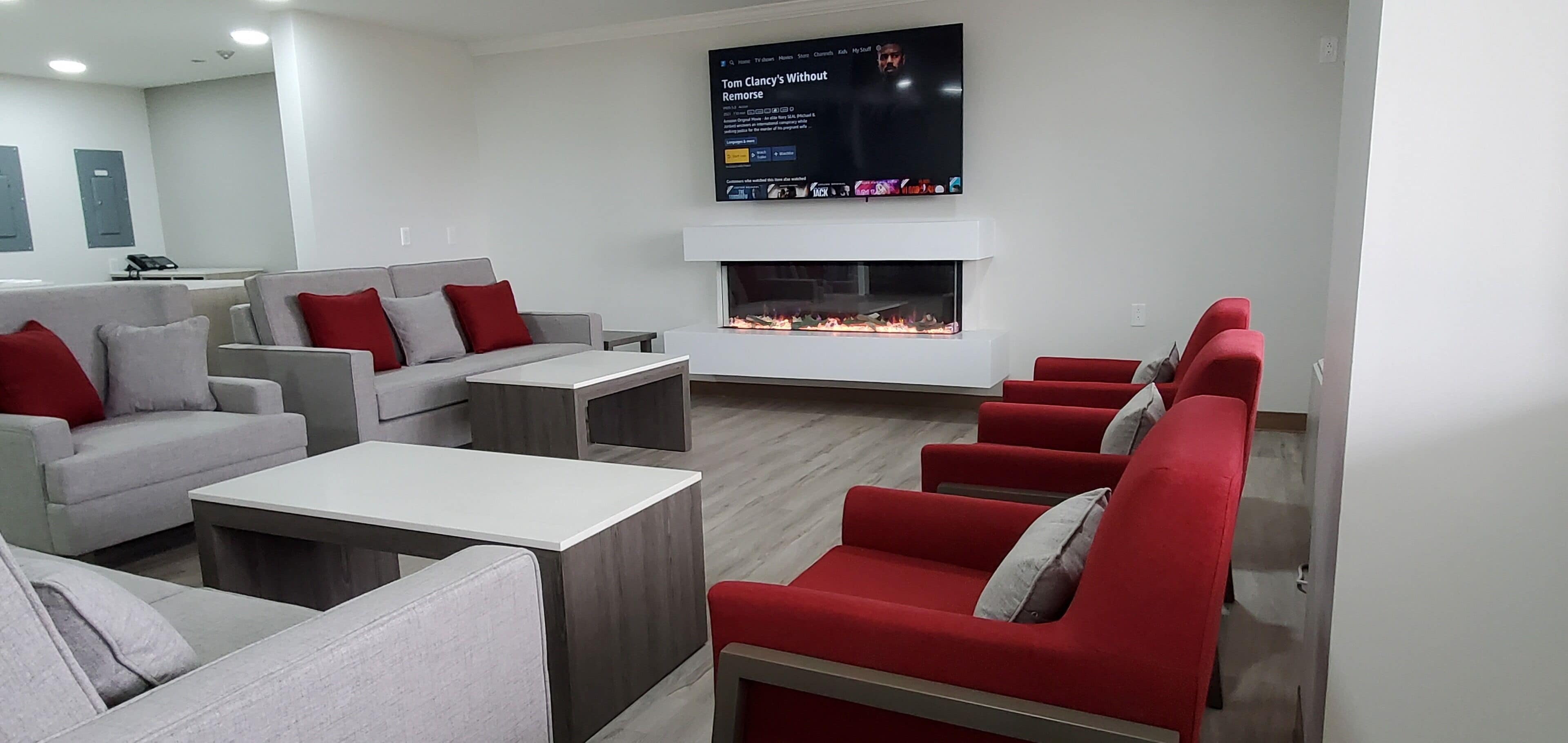 A modern living room with grey and red sofas, a flat-screen TV, and a fireplace.