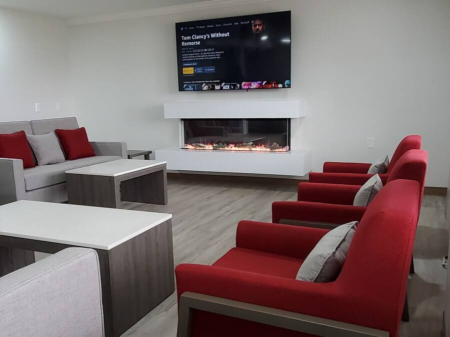 A modern living room with grey and red sofas, a flat-screen TV, and a fireplace.
