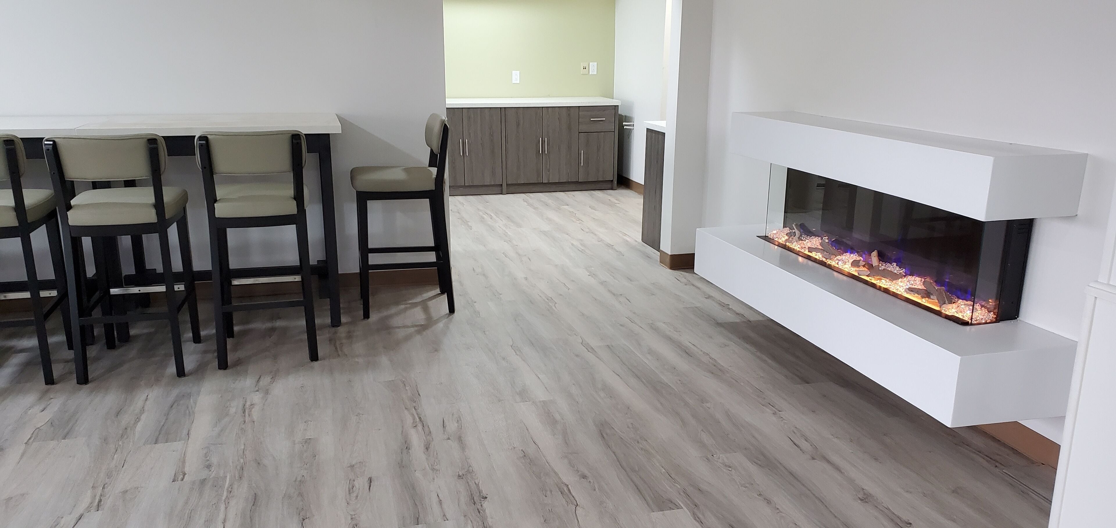 A modern living room with a dining area, a fireplace, and light-colored wooden flooring.