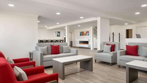 Uma sala de estar moderna com sofás cinzas e poltronas vermelhas, uma lareira e uma escada.