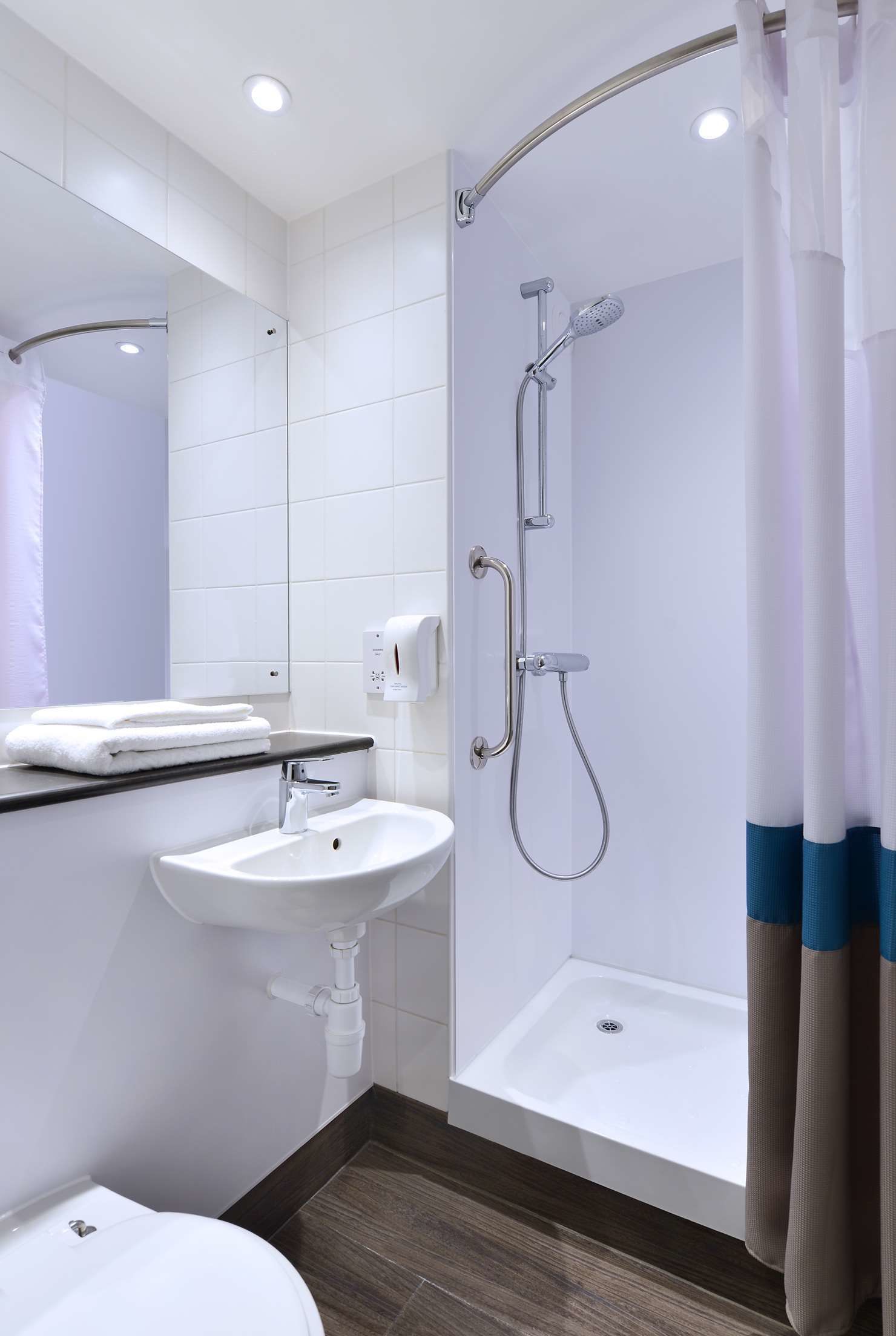 A modern bathroom with a shower, sink, and toilet.