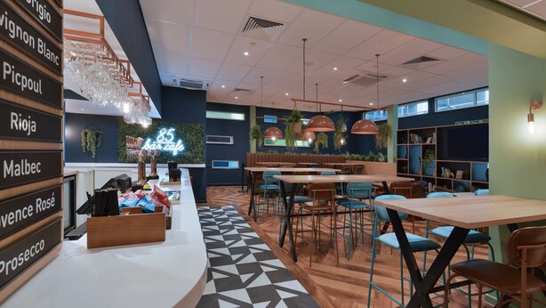 A restaurant with a modern interior, featuring a bar area with wine glasses, a patterned floor, and seating arrangements. - Travelodge London Covent Garden (London)
