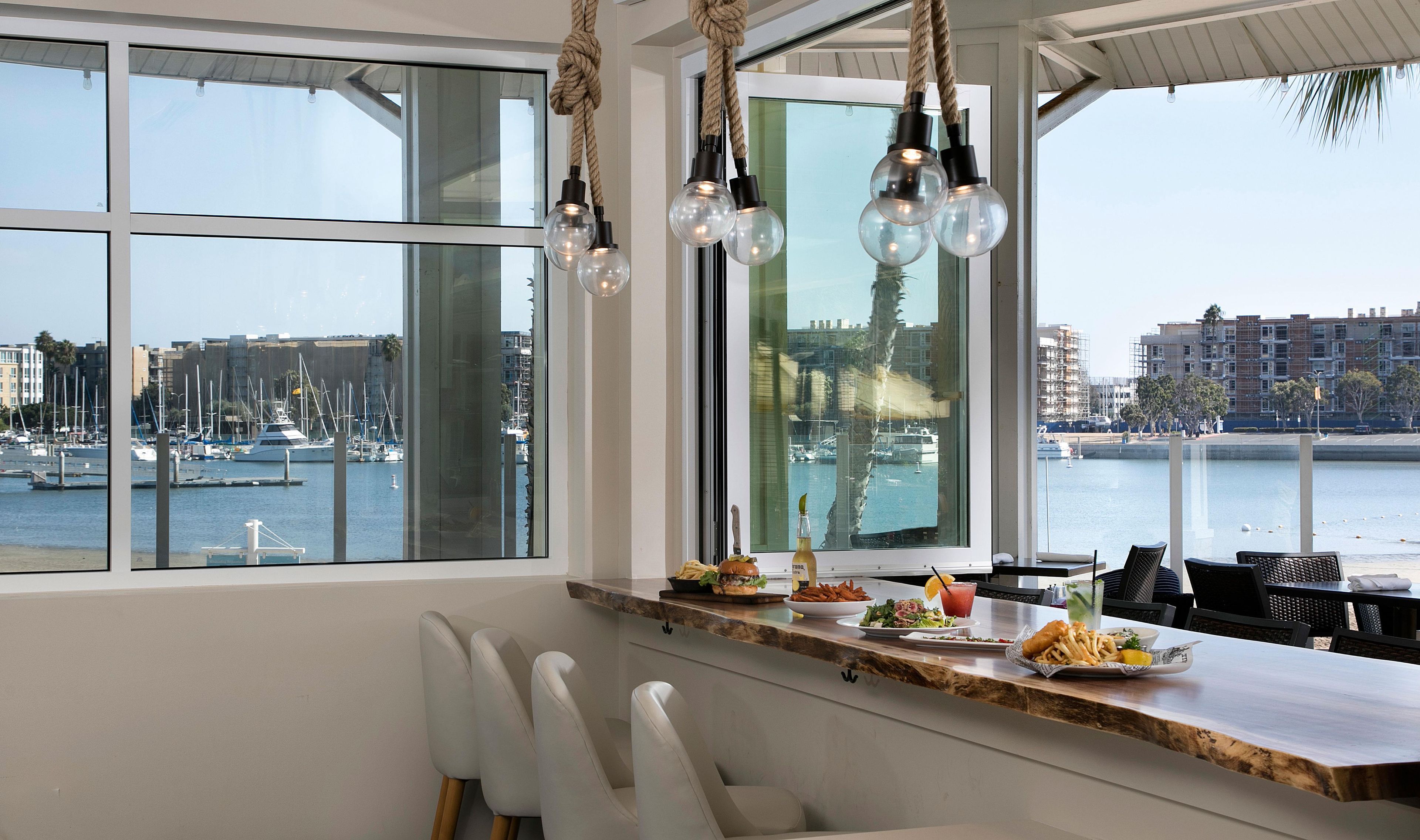 Een eetgedeelte met uitzicht op een jachthaven, een houten bar en een zithoek.