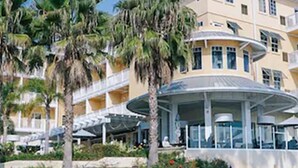 Ein Hotel mit Poolbereich, Palmen und einem Gebäude mit mehreren Balkonen.