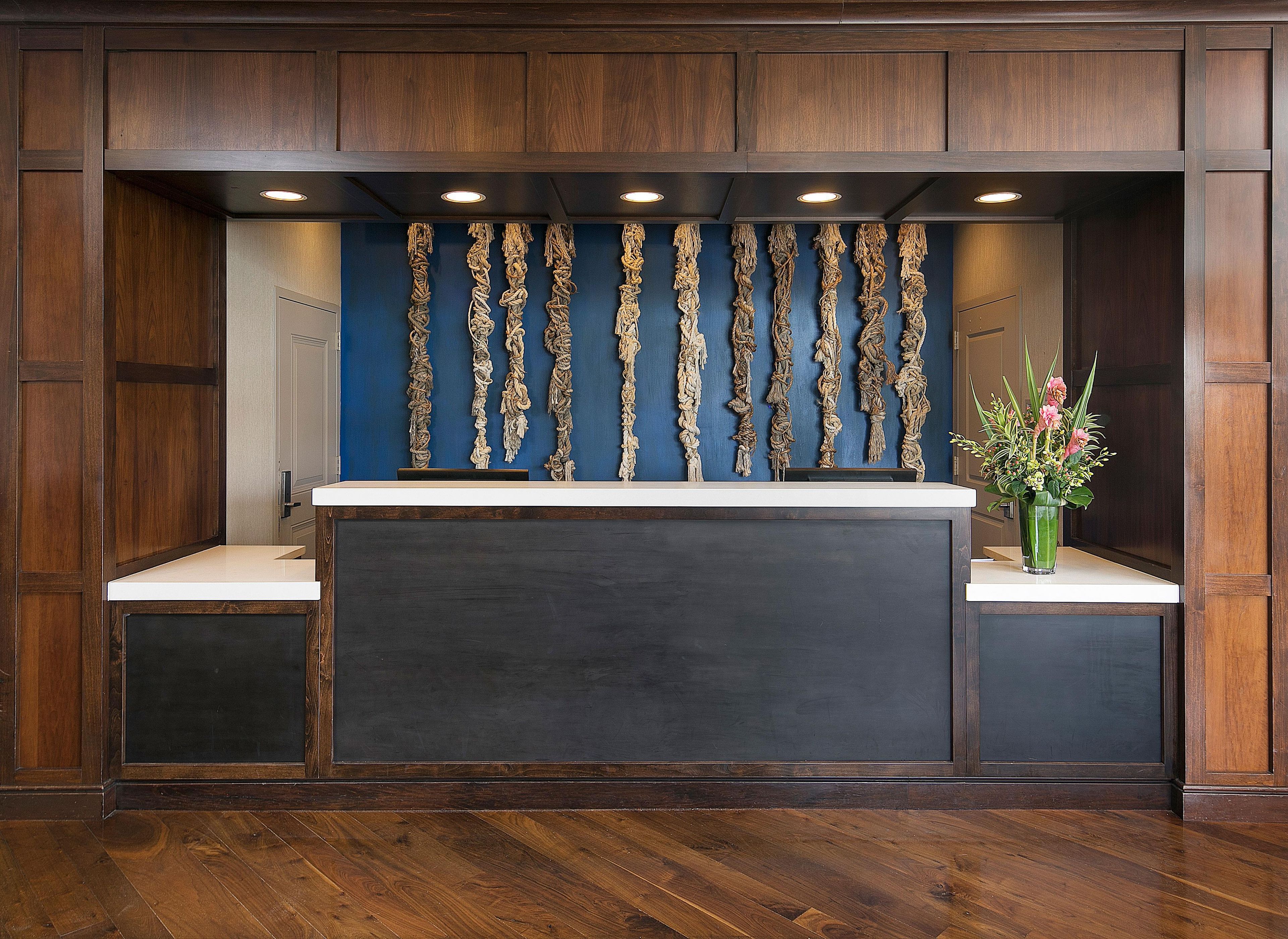 A reception desk with a dark counter, wooden paneling, and a blue wall with hanging decorations.