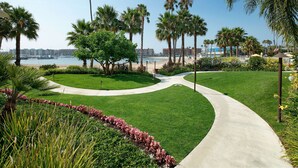 Ein gepflegter Garten mit einem gewundenen Weg, der zum Strand, Palmen und einem klaren Blick auf den Ozean führt.