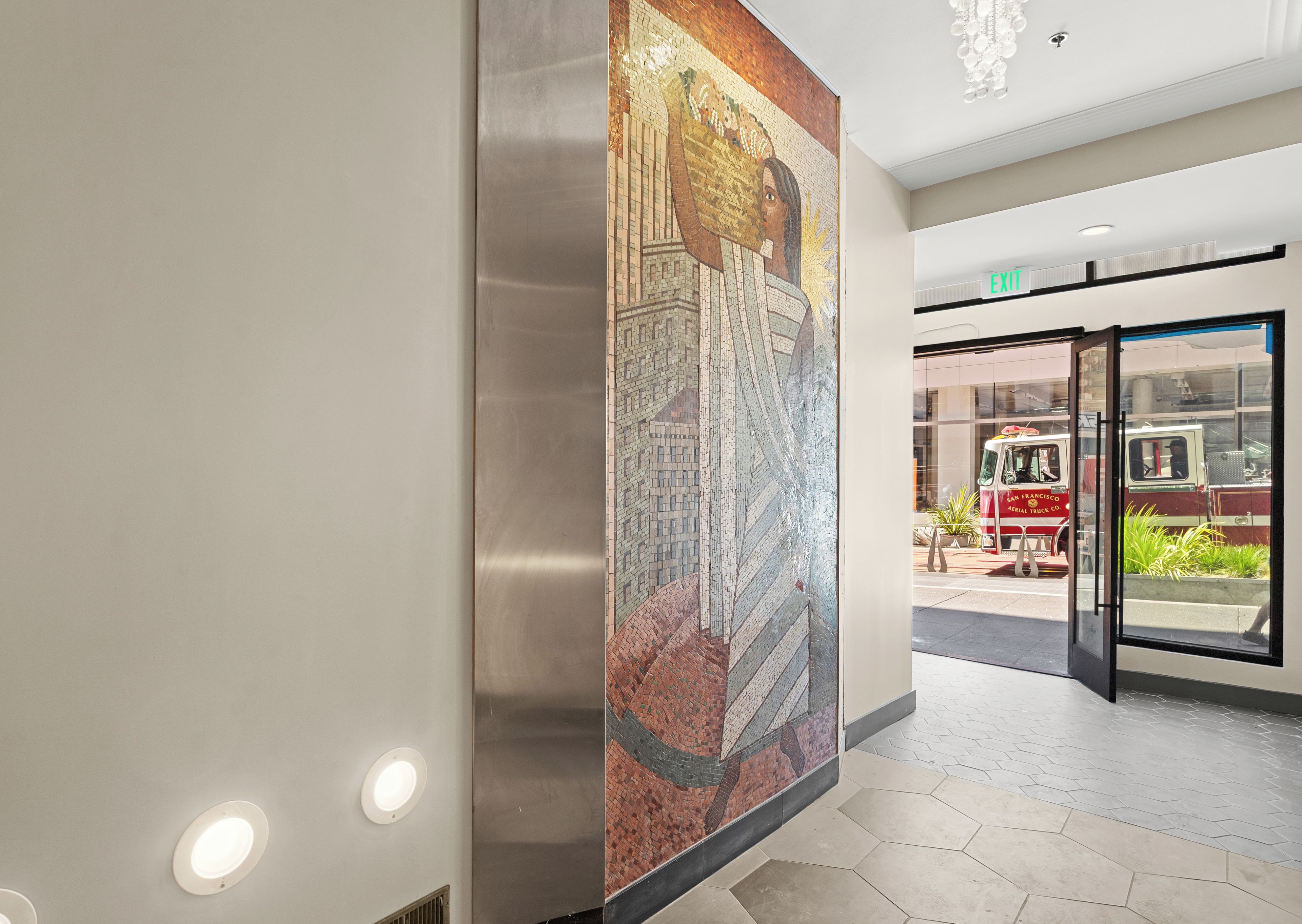 Ein modernes Interieur mit einer Mosaikwand, einem Glastür-Eingang und einer Deckenleuchte.