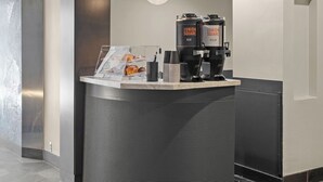A concierge desk with a hexagonal patterned wall, a modern pendant light, and a coffee machine.