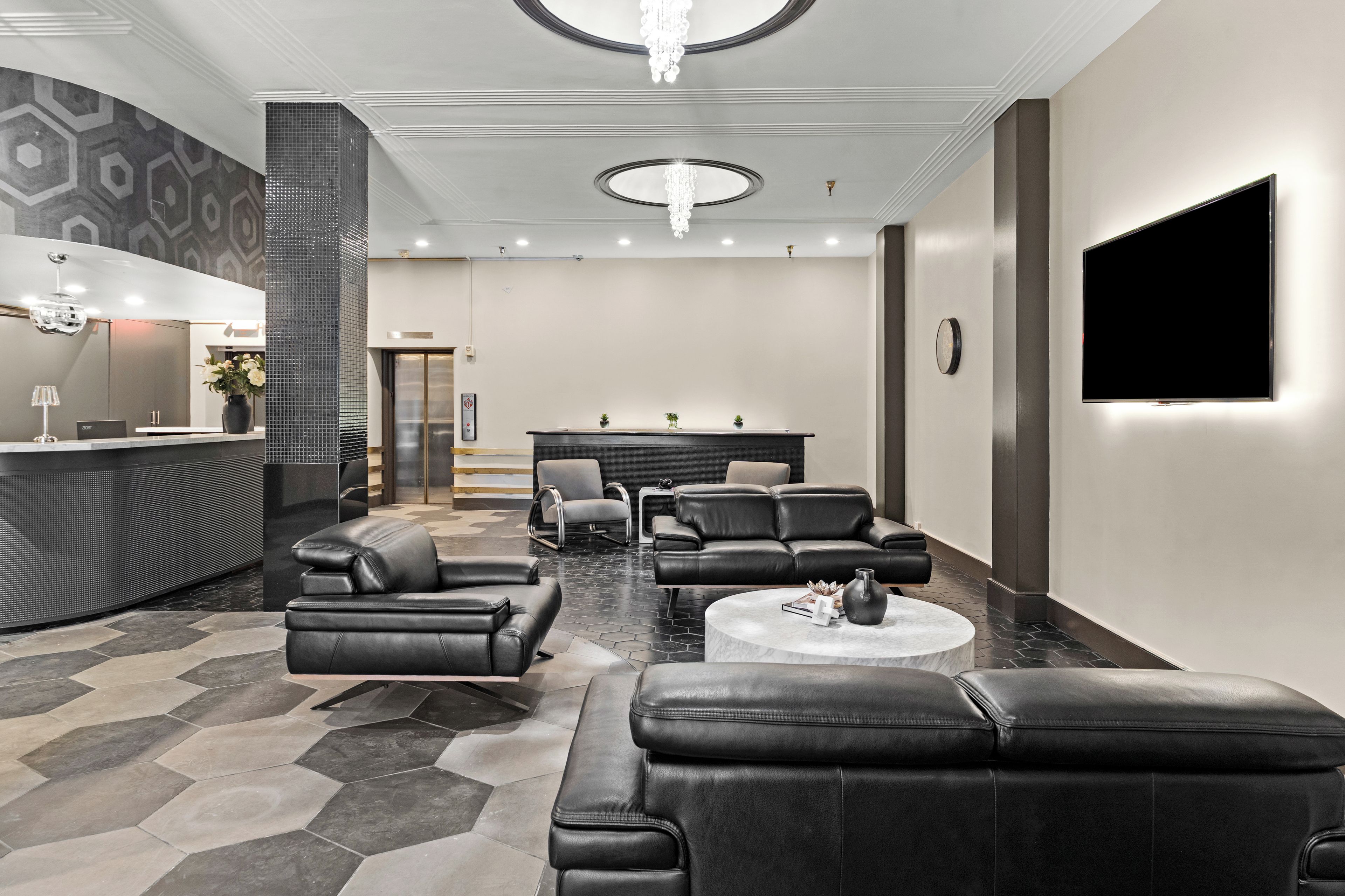 A modern lobby with leather seating, a reception desk, and a flat-screen TV.