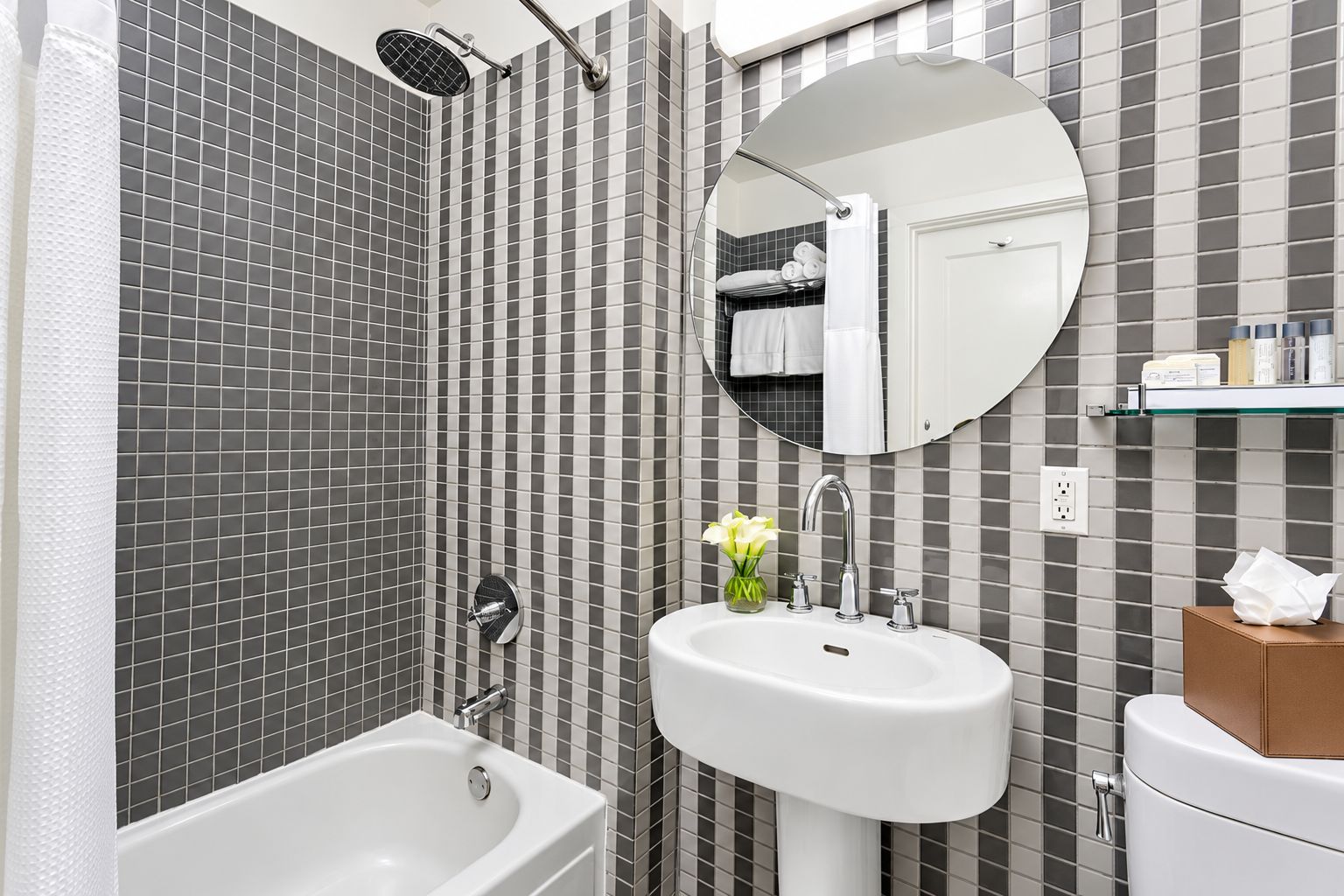 A bathroom with a bathtub, a sink, a mirror, and a shower.