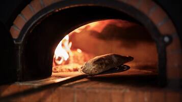 A pizza inside a brick oven with flames visible.