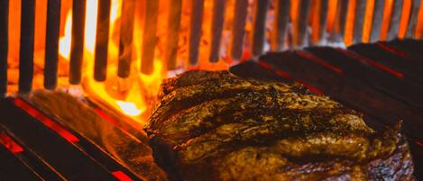 A steak grilling over an open flame.