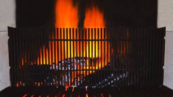 A fireplace with a metal grate, burning logs, and visible flames.