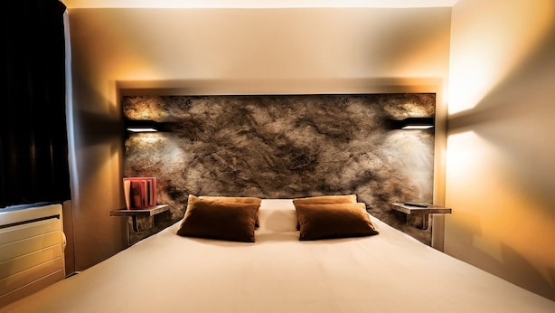 A bedroom with a large bed, two bedside tables, and a wall-mounted light fixture.