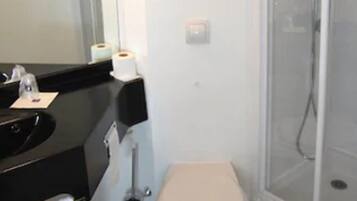 Een badkamer met toilet, wastafel, spiegel en een douchecabine.