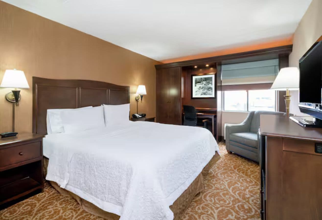 Une chambre d’hôtel avec un grand lit, un bureau, une chaise et un téléviseur.