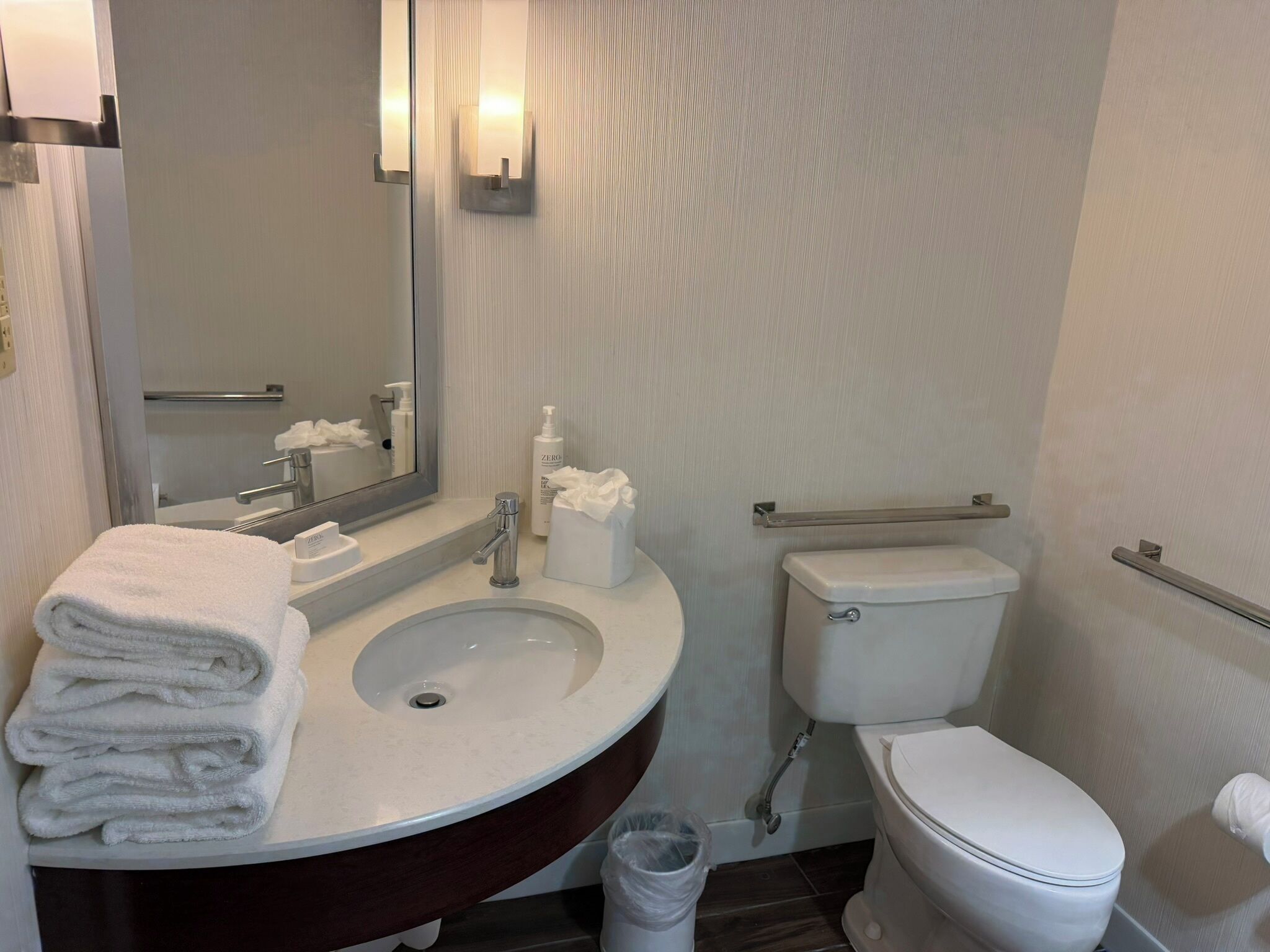 Ein Badezimmer mit Waschbecken, Spiegel, Toilette und Mülleimer.