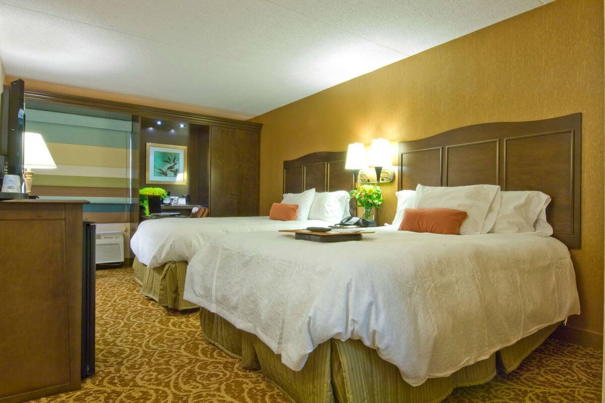 A hotel room with a double bed, a desk, a mirror, and a lamp.