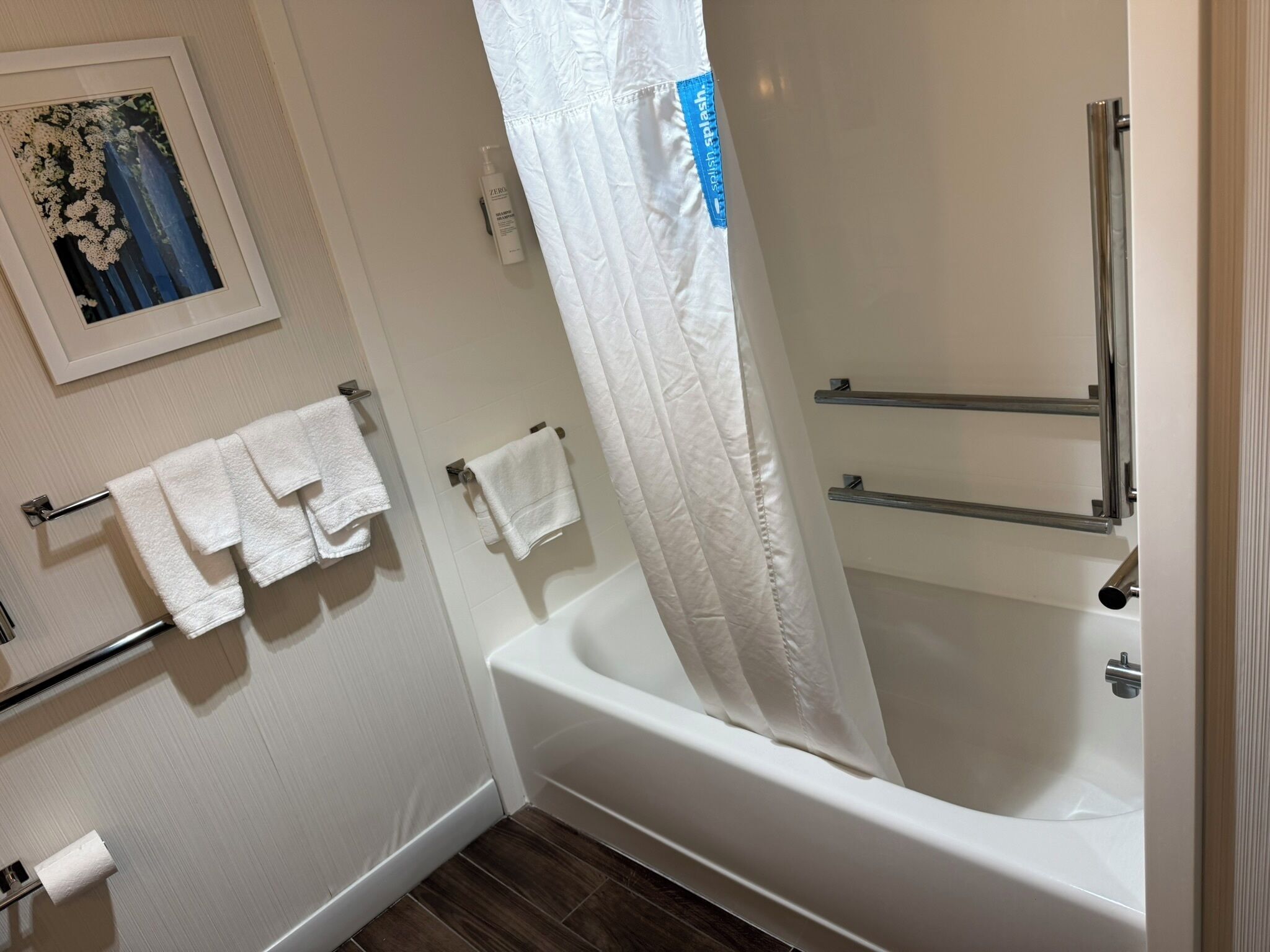 A bathroom with a bathtub, a shower curtain, and two towel racks with towels.