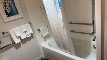 A bathroom with a bathtub, a shower curtain, and two towel racks with towels.