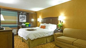 A hotel room with a bed, a desk, a sofa, and a lamp.