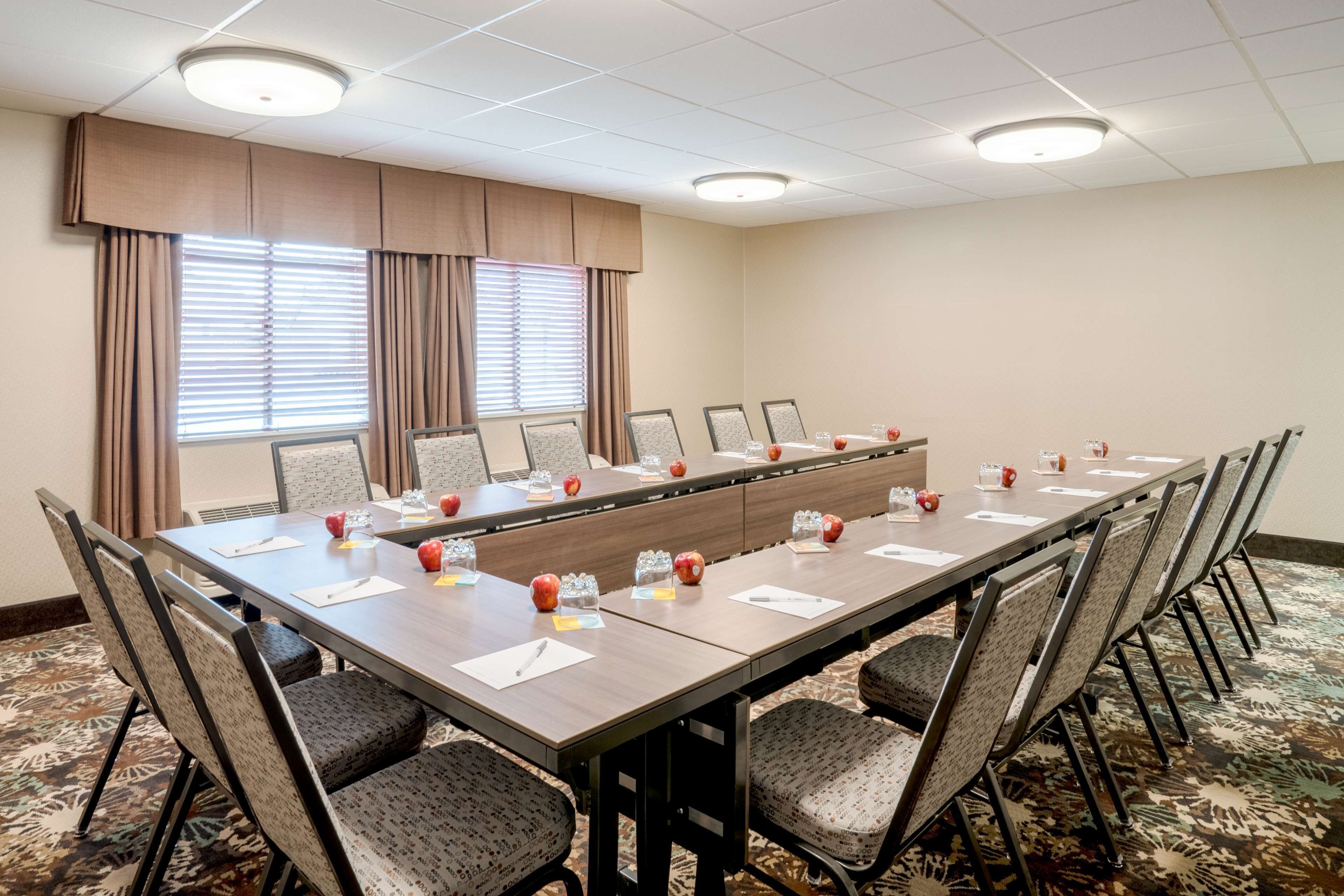 A conference room with a long table, chairs, and a large window with curtains.