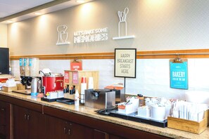 A bakery counter with coffee machines, a red coffee pot, and various bakery items.