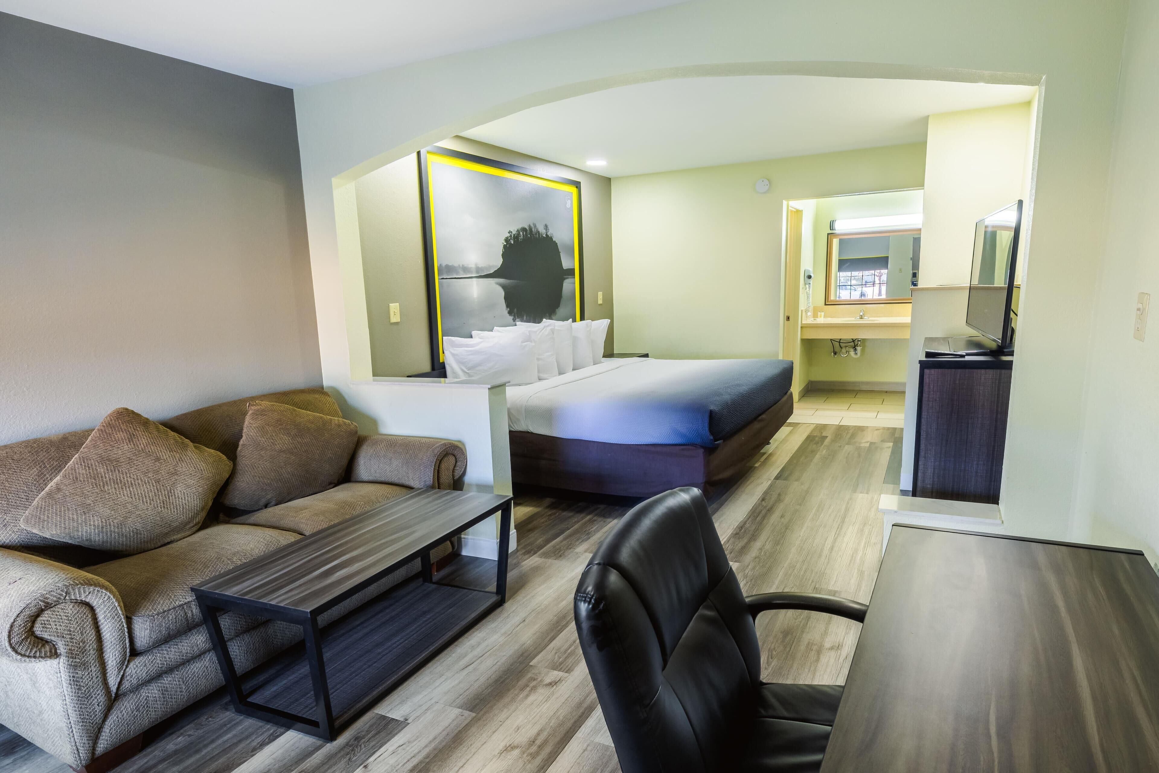 Quarto de hotel moderno com sofá, cama, escrivaninha e cadeira.