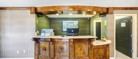 A reception desk with a wooden design, a computer, and a framed picture on the counter.