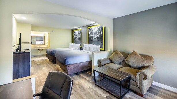 A modern hotel room with a bed, a sofa, a desk, and a chair.